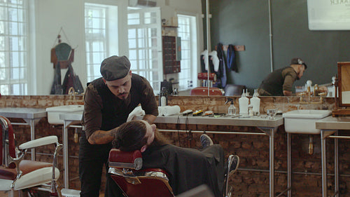 Barber cutting beard with scissors at barbershop
