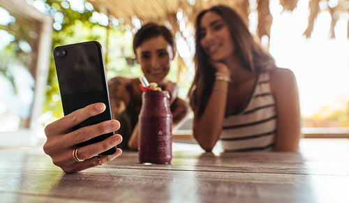 Friends taking selfie with a smoothie on the table