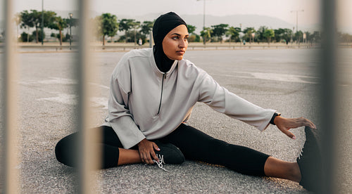 Woman with a hijab doing stretch exercises outdoors