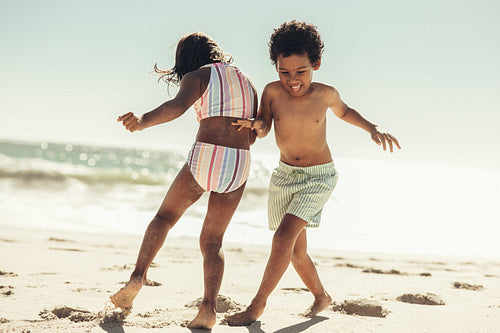 Active little kids playing together on beach sand