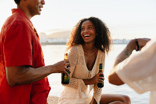 Young woman laughing with friends by the water at sunset