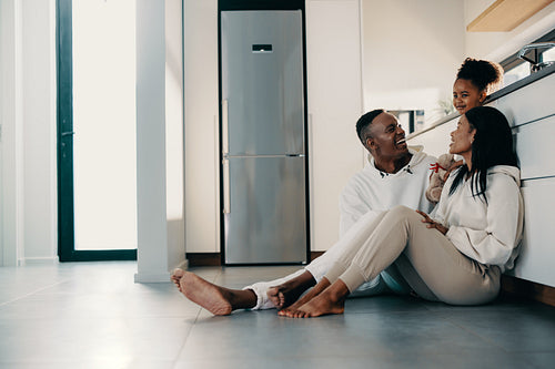 Mom and dad sitting on the kitchen floor with their daughter
