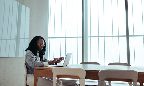 Hardworking African businesswoman focused on her laptop in a modern office