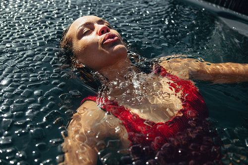 A floating woman relaxes in an outdoor ice bath for recovery and wellness.