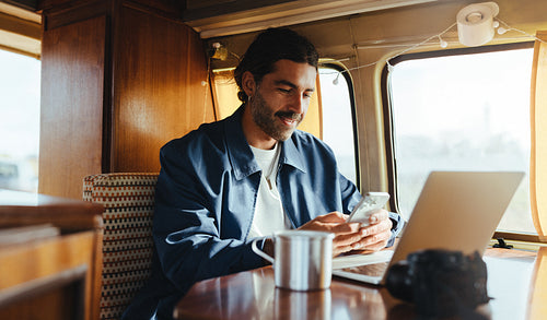 Man works on laptop inside a cozy camper van during travel
