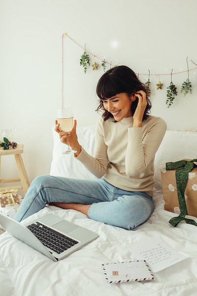 Woman on video call celebrating christmas with wine