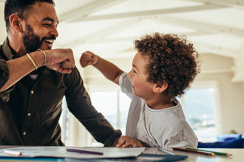 Smiling kid giving a fist bump to his father