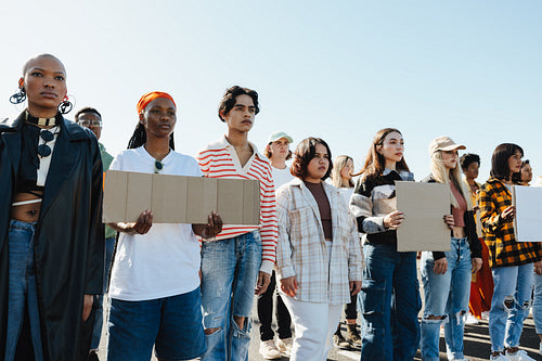 Group of diverse young individuals holding signs in a peaceful outdoor setting