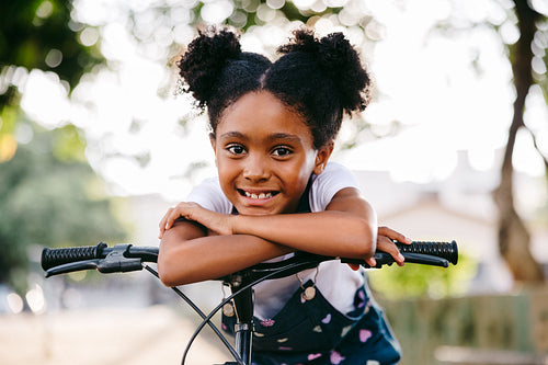 Happy young girl leaning on her bicycle in the park