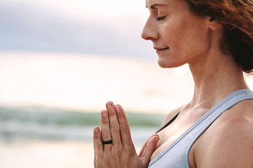 Close up of a woman doing yoga standing at the beach