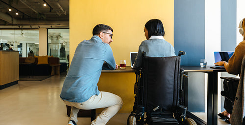 Two office colleagues communicate in a modern workspace to discuss ideas