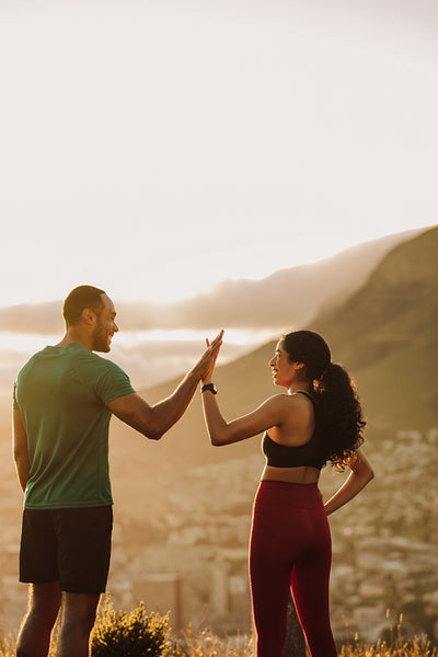 Fitness couple standing outdoors giving high five