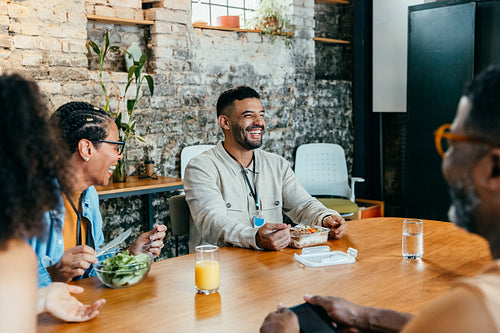 Colleagues enjoying a relaxed lunch hour together in bright office with thriving indoor plants