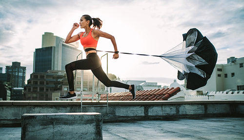 Woman running on rooftop with a resistance parachute