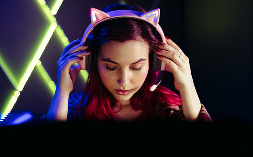 Getting into the game, girl adjusts her gaming headset at night