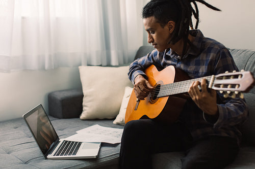 Black male guitarist having online lessons at home