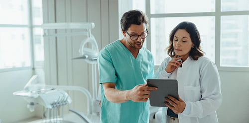 Dental professionals review patient treatment on tablet in clinic