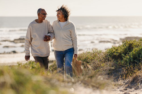 Mature couple smiling happily while leaving the beach