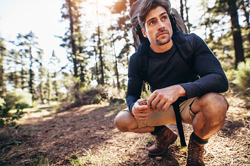Man sitting on forest trail wearing a backpack