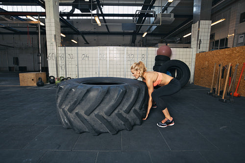 Female athlete flipping a tire while working out