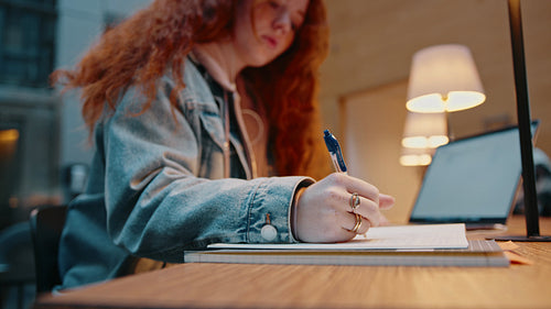 Preparing for an exam: College girl studying in a library, using a laptop to access her study material online