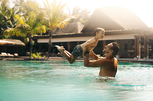 Father and son enjoying playful moments at tropical resort pool