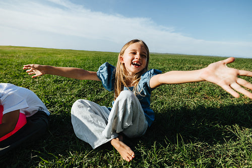 Girl on grass with open arms smiles at camera