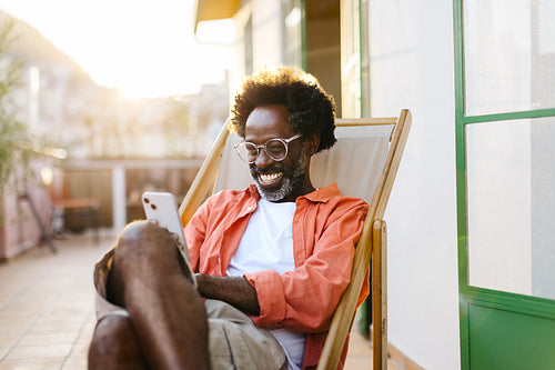 Cheerful mature man enjoying a video chat on his smartphone outdoors