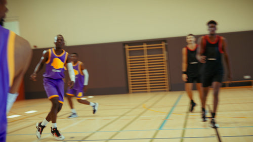 Men playing competitive basketball indoors