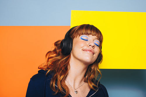 Carefree woman listening to relaxing music while standing in front of two placards