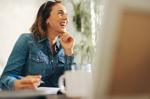 Successful and happy businesswoman writing in her office