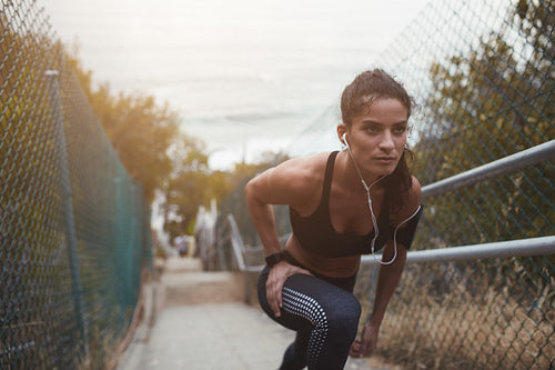 Female athlete doing stretching workout on steps outdoors