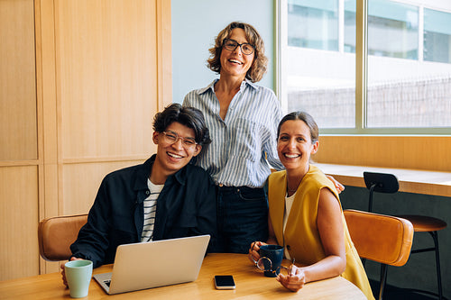 Happy coworkers enjoying coffee and discussing a project in a modern office