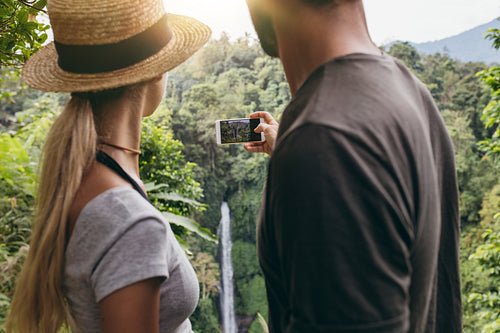 Young couple taking a picture of water fall