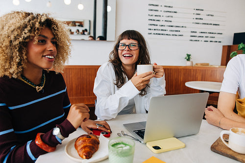 Friends working over coffee in a bright cafe