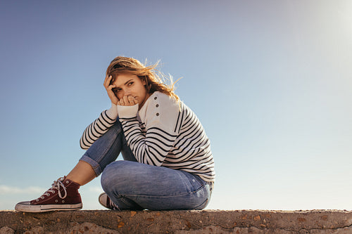 Woman sitting on a sea wall looking away