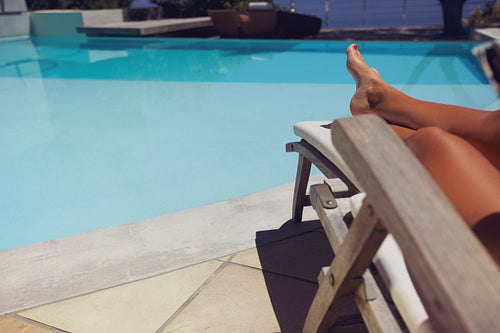 Woman relaxing on a recliner by poolside