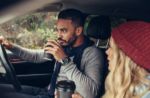 Couple drinking coffee while driving a car