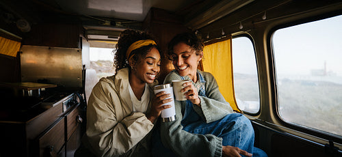 Friends share coffee and smiles inside a cozy van
