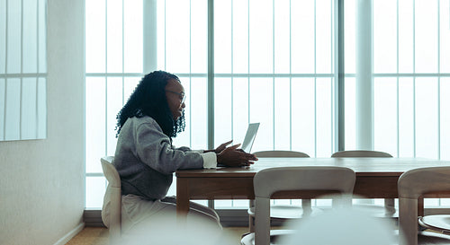 Young professional woman engaged in virtual meeting on laptop in a bright, contemporary office