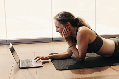 Cheerful senior woman joining a virtual yoga class on a laptop
