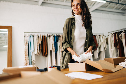 Dedicated female entrepreneur preparing orders for dropshipping in her clothing store