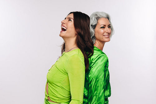 Women of diverse ages standing back to back laughing together