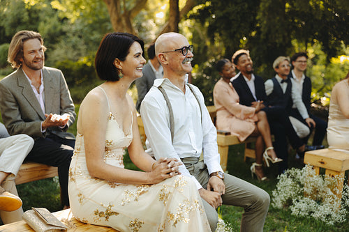Elegant guests attending an outdoor wedding ceremony in a serene garden setting