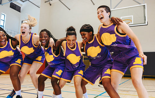 Group of female basketball players celebrating together on an indoor court