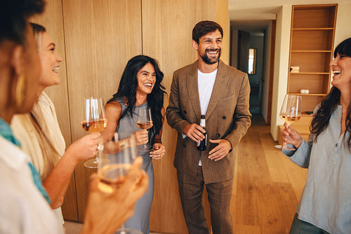 Group of friends laughing and having drinks in a modern home