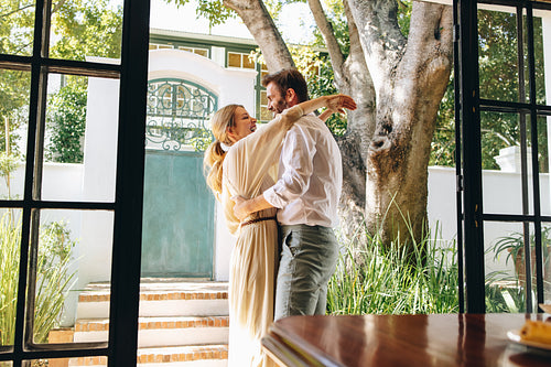Smiling couple embracing each other outside a hotel entrance