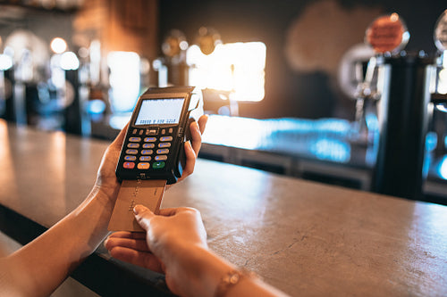 Hands of woman doing cashless payment at bar