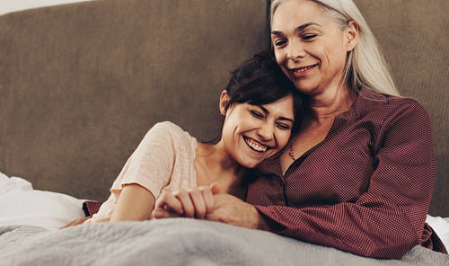 Mother and daughter sitting on bed together