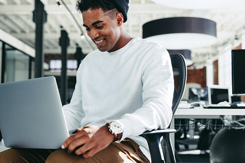 Smiling businessman working on a laptop in a modern office